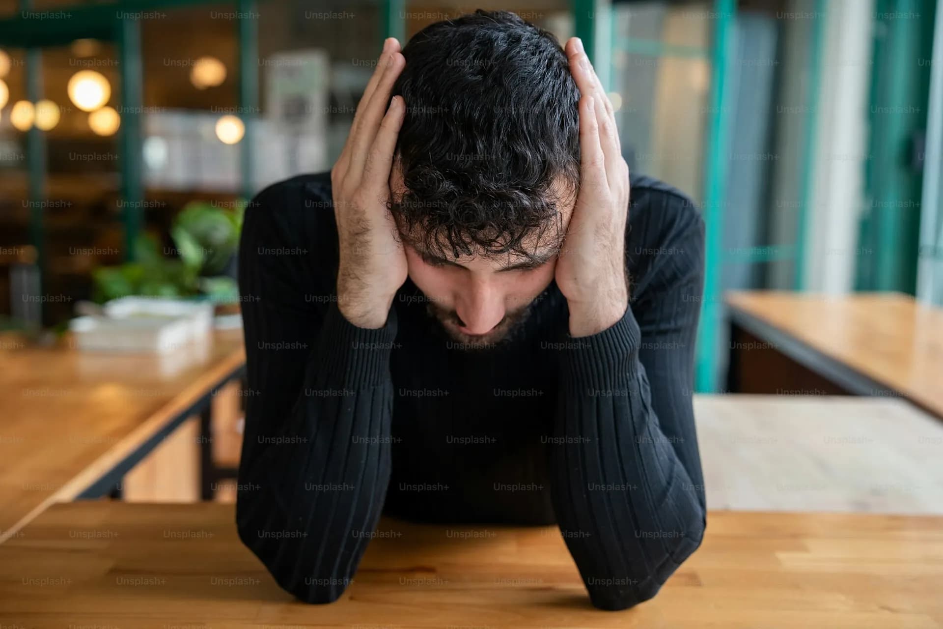 A man at a table with his head in his hands.