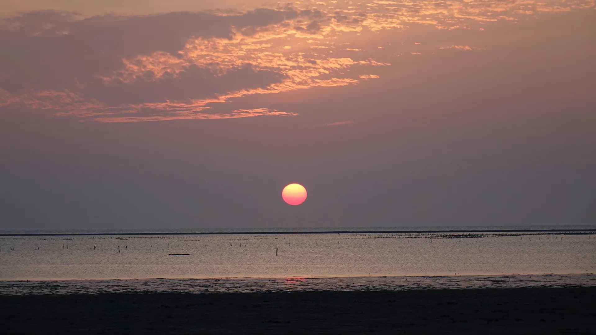 A cloudy sky at sunset, low orange light under grey cloud